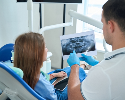 Orthodontist showing a patient x rays of their teeth on a tablet
