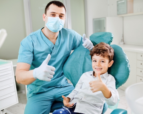 Orthodontist and young boy in treatment chair both giving a thumbs up