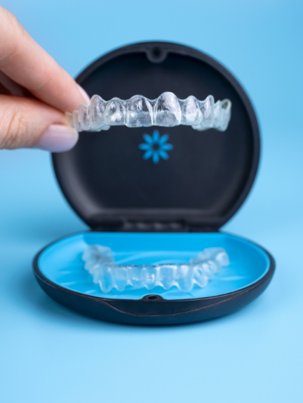 Hand placing an Invisalign clear aligner into its carrying case