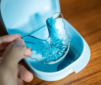 Hand placing a clear removable retainer into its storage case