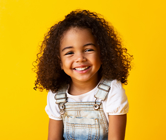 Young girl with overalls grinning