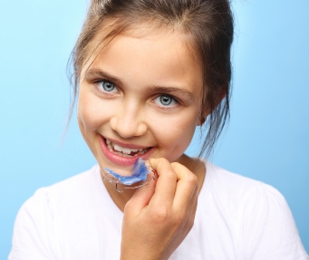 Young girl holding a blue retainer