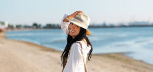 Woman with straw hat enjoying a walk on the beach while wearing Invisalign.