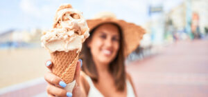Woman smiling enjoying an ice cream cone outdoors while wearing braces.