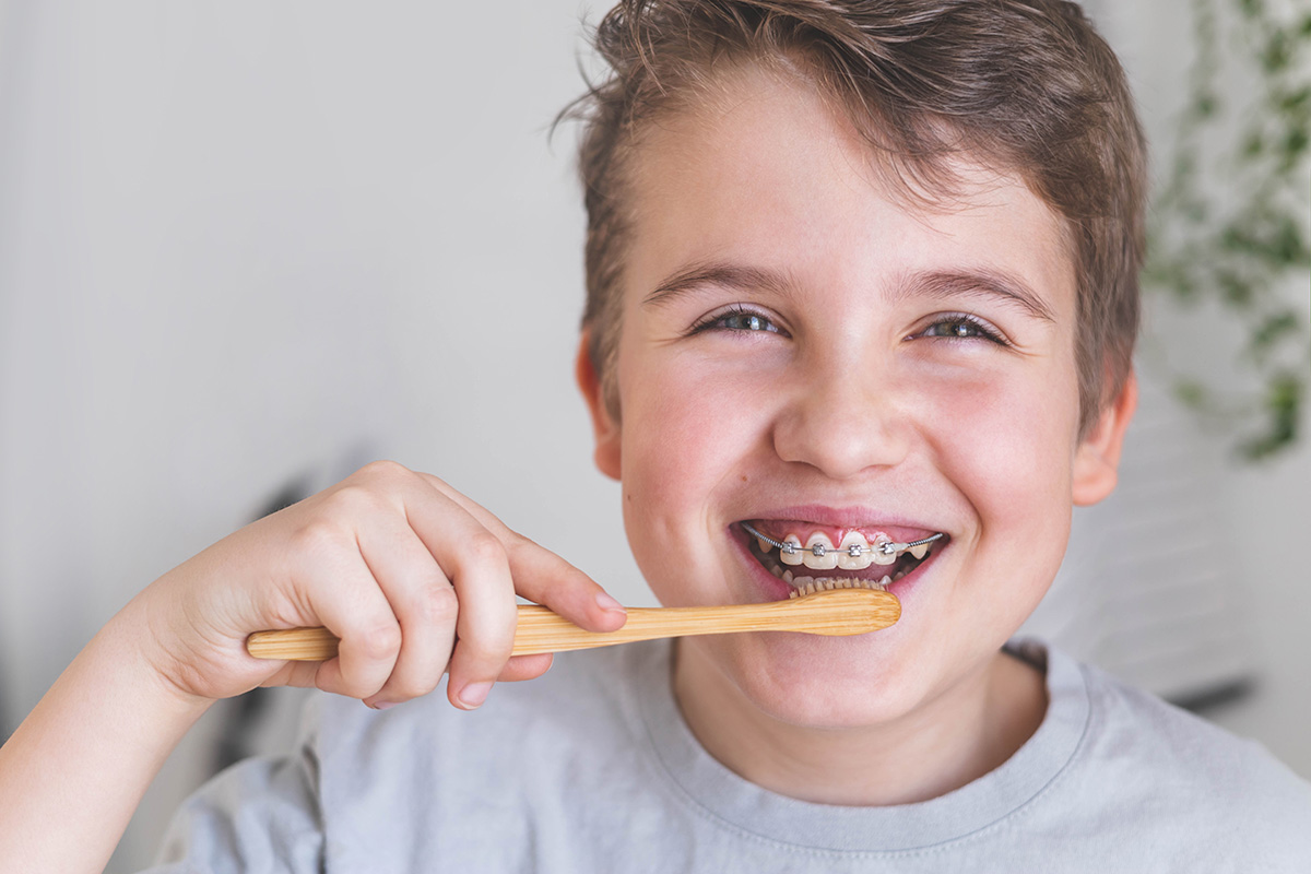 Happy boy with braces brushing his teeth.