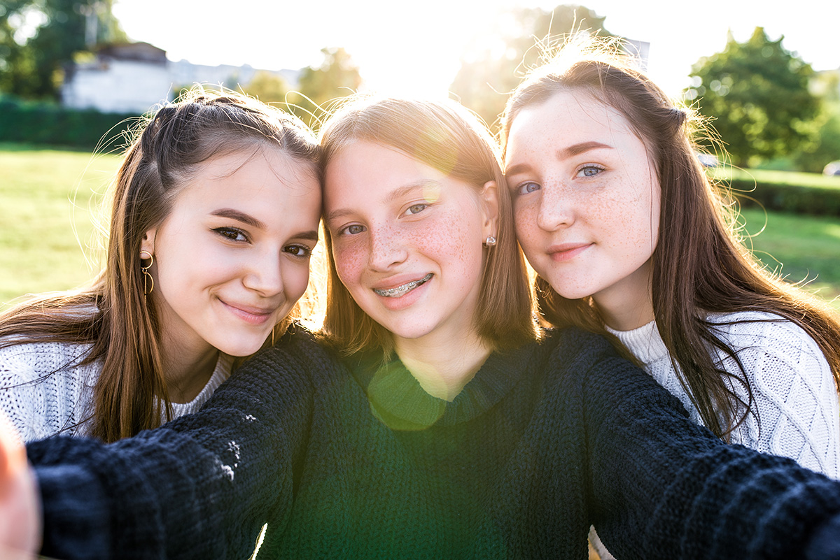 3 girls taking aselfie photo on phone camera, after school. 