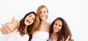 A girl with braces taking a picture with her friends.