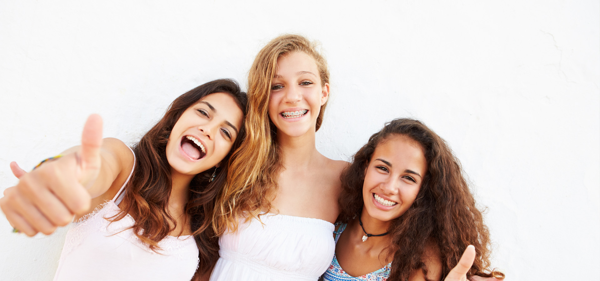 A girl with braces taking a picture with her friends.