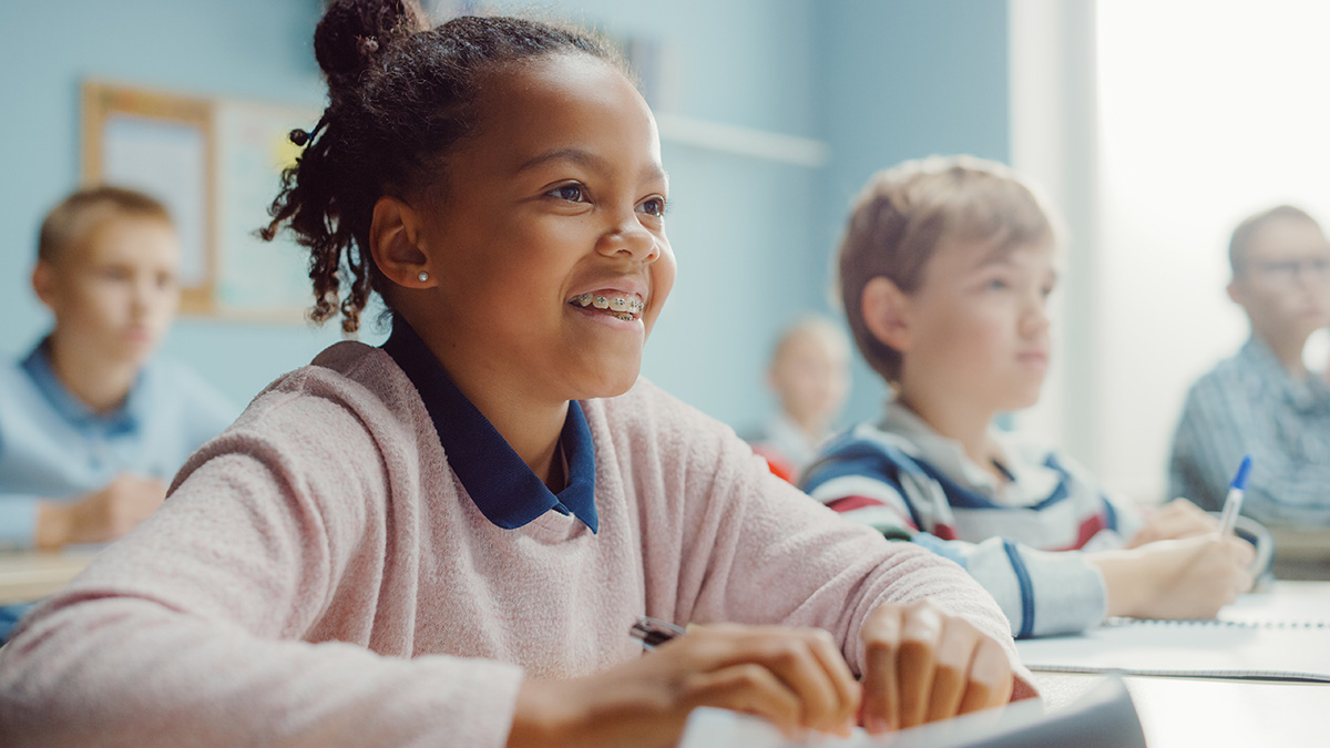 Girl with braces smiling in a classroom.