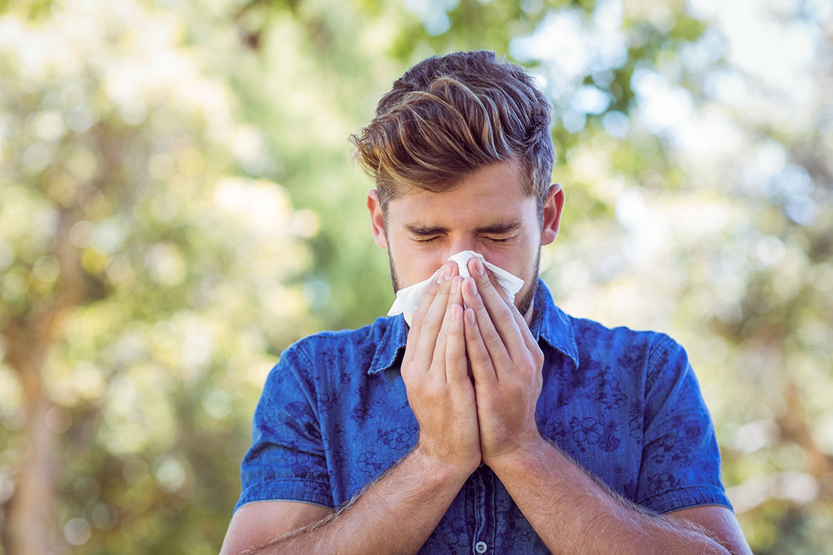Man with pollen allergies blowing his nose