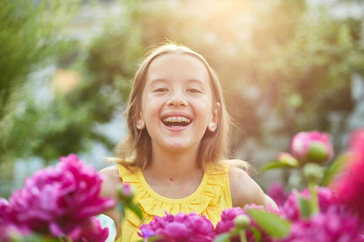 Happy little girl with braces in the garden